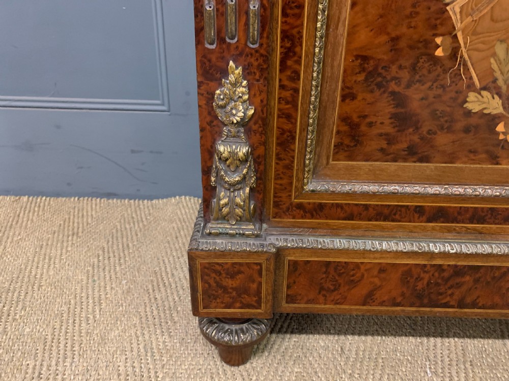 A 19th-century French double-door bookcase featuring amboyna and mahogany veneers, intricate floral marquetry, pleated cream fabric door panels, and brass mounts. View VI