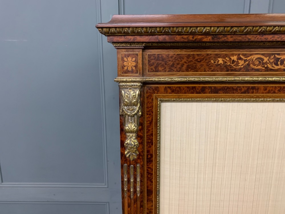 A 19th-century French double-door bookcase featuring amboyna and mahogany veneers, intricate floral marquetry, pleated cream fabric door panels, and brass mounts. View IX