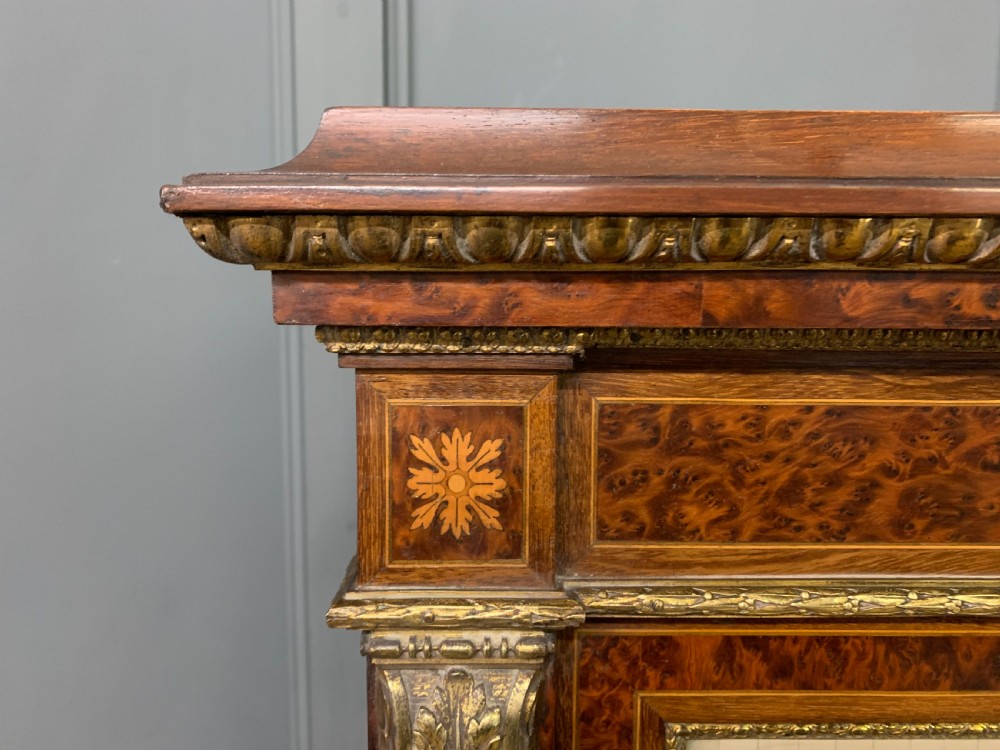 A 19th-century French double-door bookcase featuring amboyna and mahogany veneers, intricate floral marquetry, pleated cream fabric door panels, and brass mounts. View XII