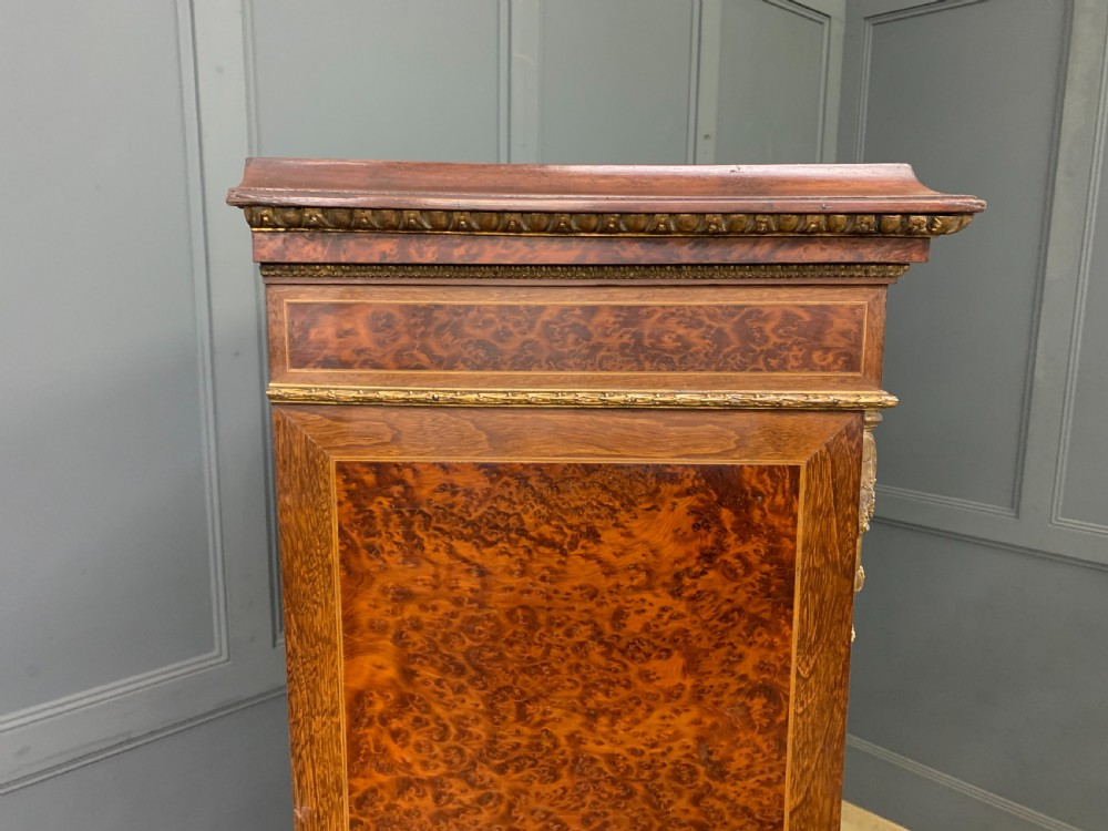 A 19th-century French double-door bookcase featuring amboyna and mahogany veneers, intricate floral marquetry, pleated cream fabric door panels, and brass mounts. View XVI