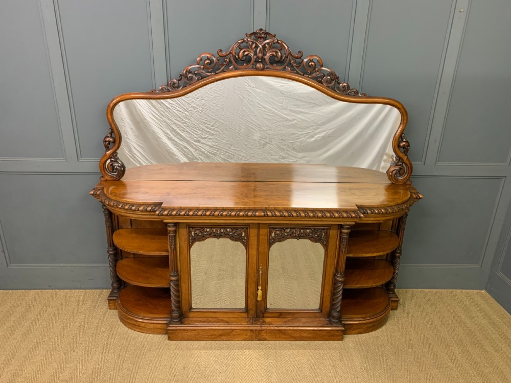 A Victorian burr walnut chiffonier featuring open side display shelves, mirrored central cabinet doors, and an ornate carved mirror frame cresting. View III
