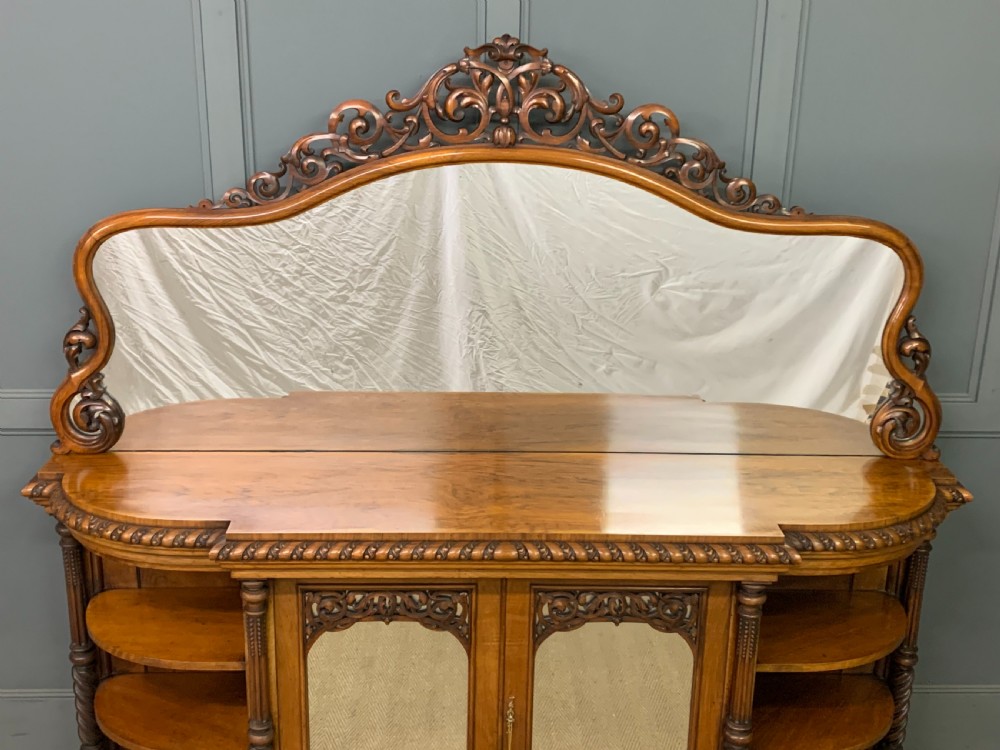 A Victorian burr walnut chiffonier featuring open side display shelves, mirrored central cabinet doors, and an ornate carved mirror frame cresting. View IV
