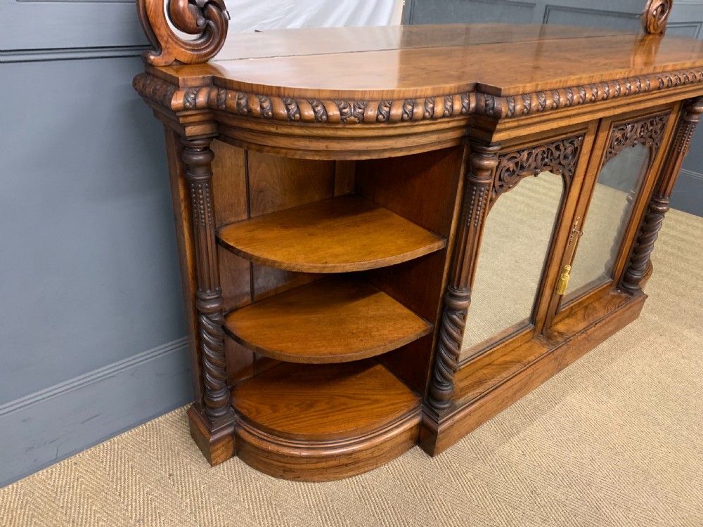A Victorian burr walnut chiffonier featuring open side display shelves, mirrored central cabinet doors, and an ornate carved mirror frame cresting. View IX