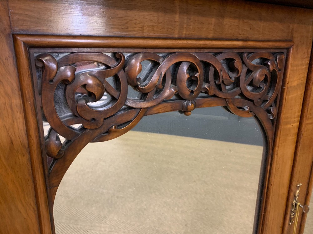 A Victorian burr walnut chiffonier featuring open side display shelves, mirrored central cabinet doors, and an ornate carved mirror frame cresting. View XXI