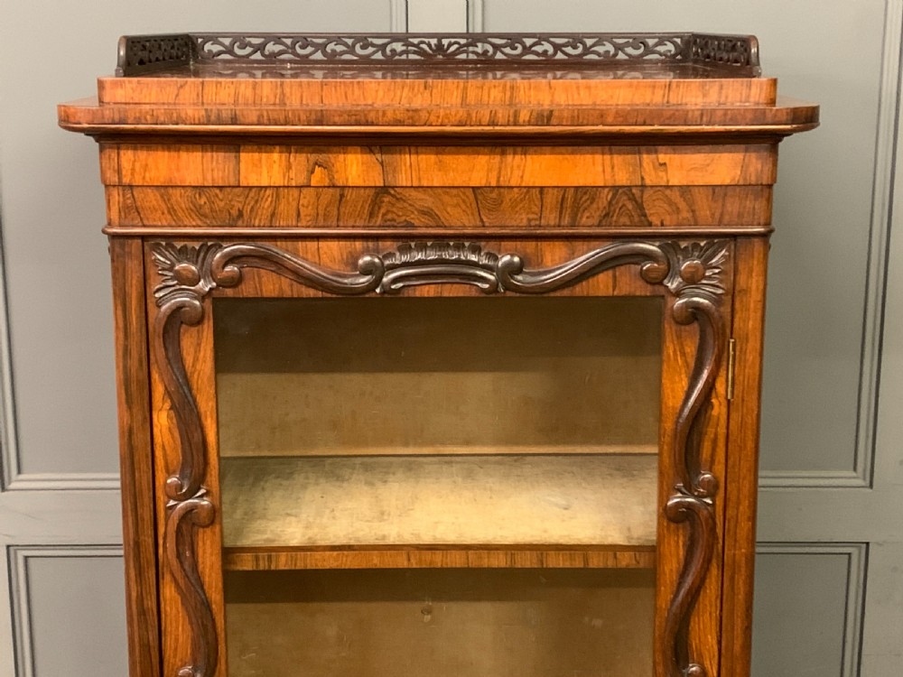 A tall Victorian rosewood bookcase cabinet featuring a single glazed door with carved scrollwork borders and a fretwork top gallery. View III