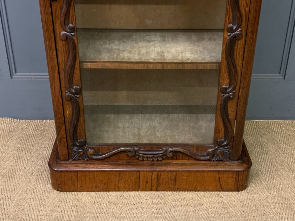 A tall Victorian rosewood bookcase cabinet featuring a single glazed door with carved scrollwork borders and a fretwork top gallery. View IV