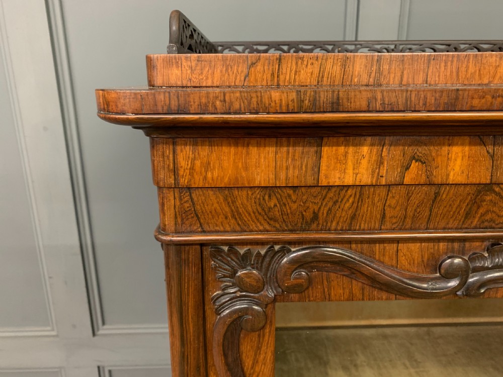 A tall Victorian rosewood bookcase cabinet featuring a single glazed door with carved scrollwork borders and a fretwork top gallery. View VI