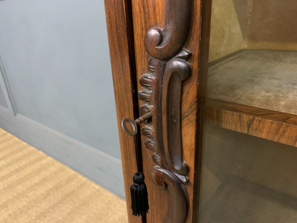 A tall Victorian rosewood bookcase cabinet featuring a single glazed door with carved scrollwork borders and a fretwork top gallery. View VII