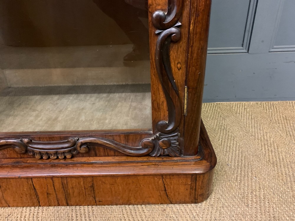 A tall Victorian rosewood bookcase cabinet featuring a single glazed door with carved scrollwork borders and a fretwork top gallery. View VIII