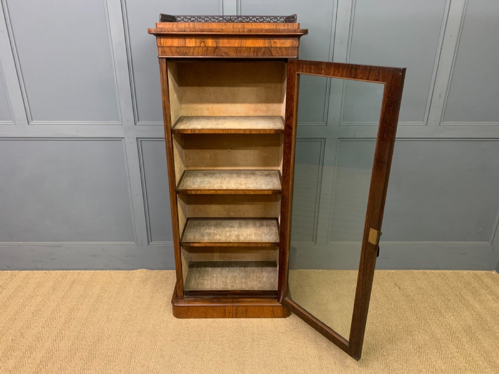 A tall Victorian rosewood bookcase cabinet featuring a single glazed door with carved scrollwork borders and a fretwork top gallery. View XI