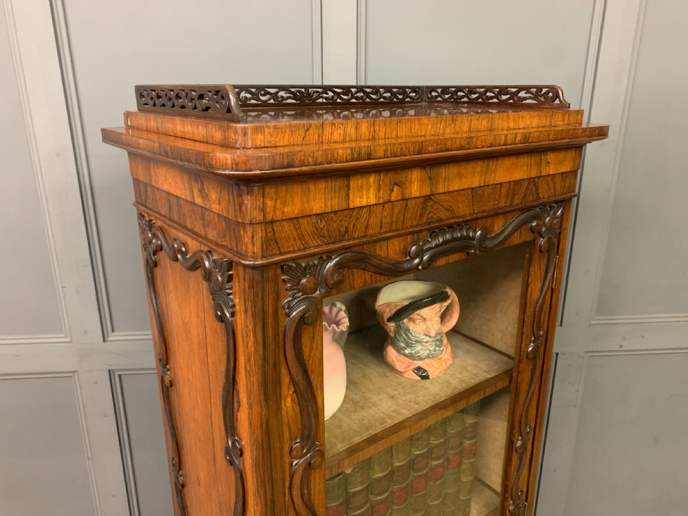 A tall Victorian rosewood bookcase cabinet featuring a single glazed door with carved scrollwork borders and a fretwork top gallery. View XVIII