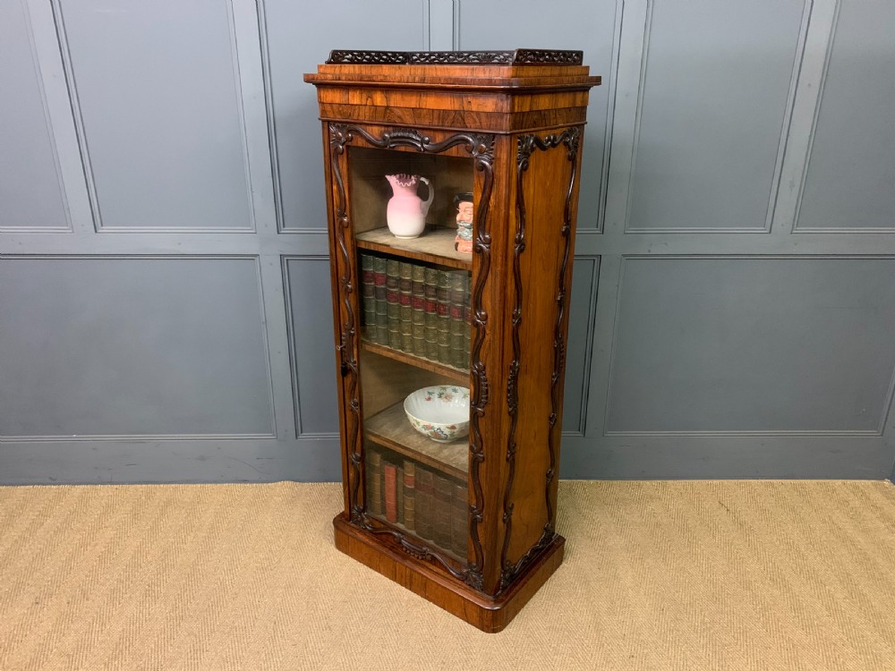 A tall Victorian rosewood bookcase cabinet featuring a single glazed door with carved scrollwork borders and a fretwork top gallery. View XX