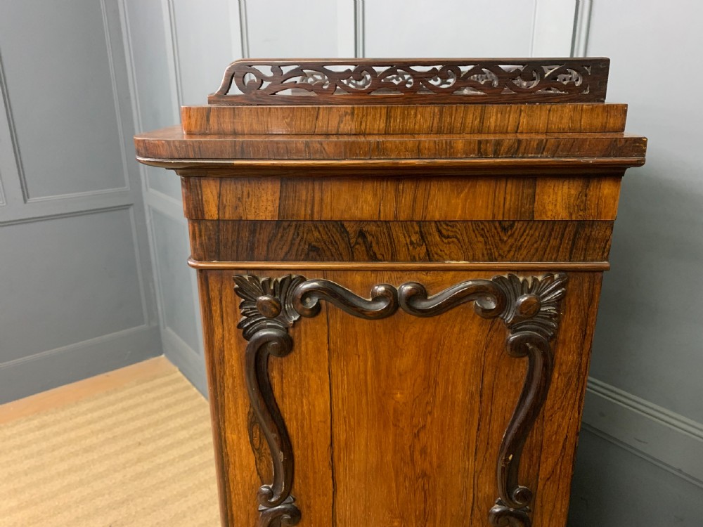 A tall Victorian rosewood bookcase cabinet featuring a single glazed door with carved scrollwork borders and a fretwork top gallery. View XXI