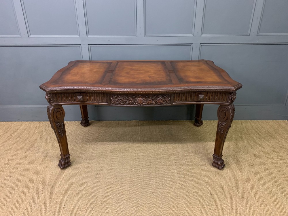 A carved mahogany writing table with a three-section inset leather top, detailed frieze carvings, and carved legs with claw feet. View II