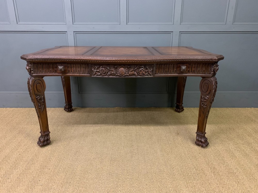 A carved mahogany writing table with a three-section inset leather top, detailed frieze carvings, and carved legs with claw feet. View III