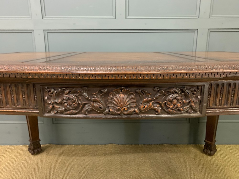 A carved mahogany writing table with a three-section inset leather top, detailed frieze carvings, and carved legs with claw feet. View V