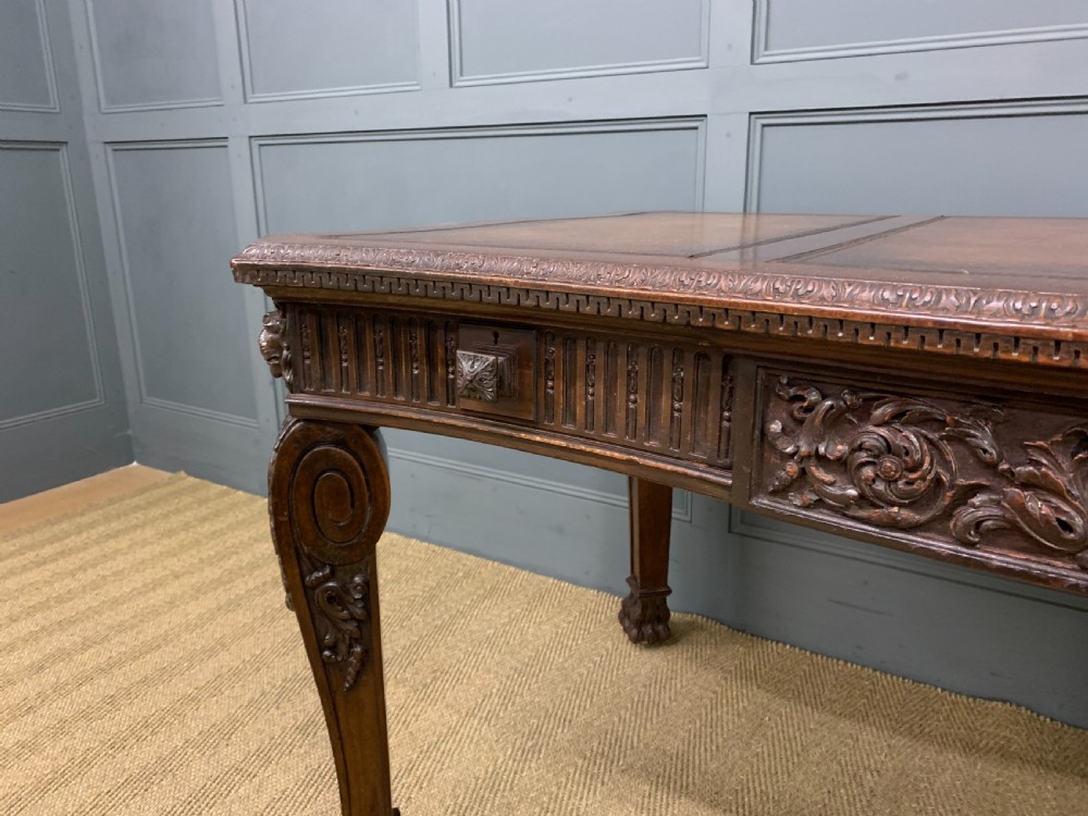 A carved mahogany writing table with a three-section inset leather top, detailed frieze carvings, and carved legs with claw feet. View VI
