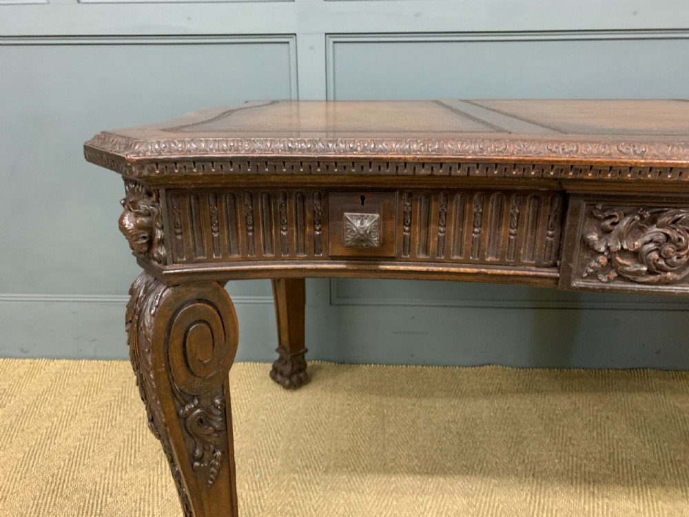 A carved mahogany writing table with a three-section inset leather top, detailed frieze carvings, and carved legs with claw feet. View VII