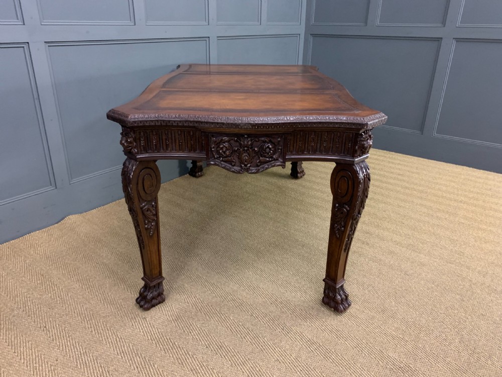 A carved mahogany writing table with a three-section inset leather top, detailed frieze carvings, and carved legs with claw feet. View XI