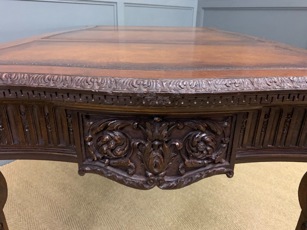 A carved mahogany writing table with a three-section inset leather top, detailed frieze carvings, and carved legs with claw feet. View XII