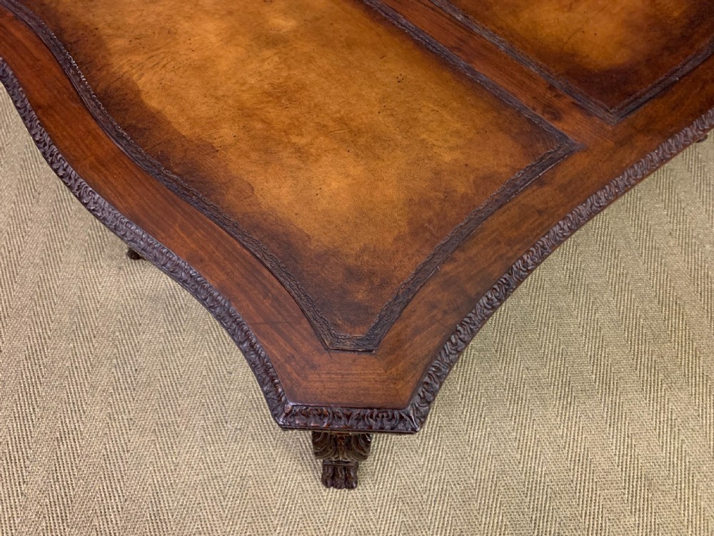 A carved mahogany writing table with a three-section inset leather top, detailed frieze carvings, and carved legs with claw feet. View XIII