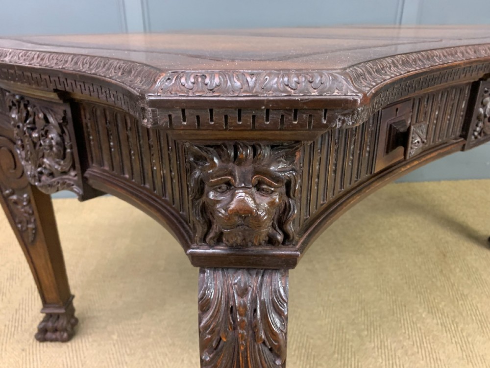 A carved mahogany writing table with a three-section inset leather top, detailed frieze carvings, and carved legs with claw feet. View XIV