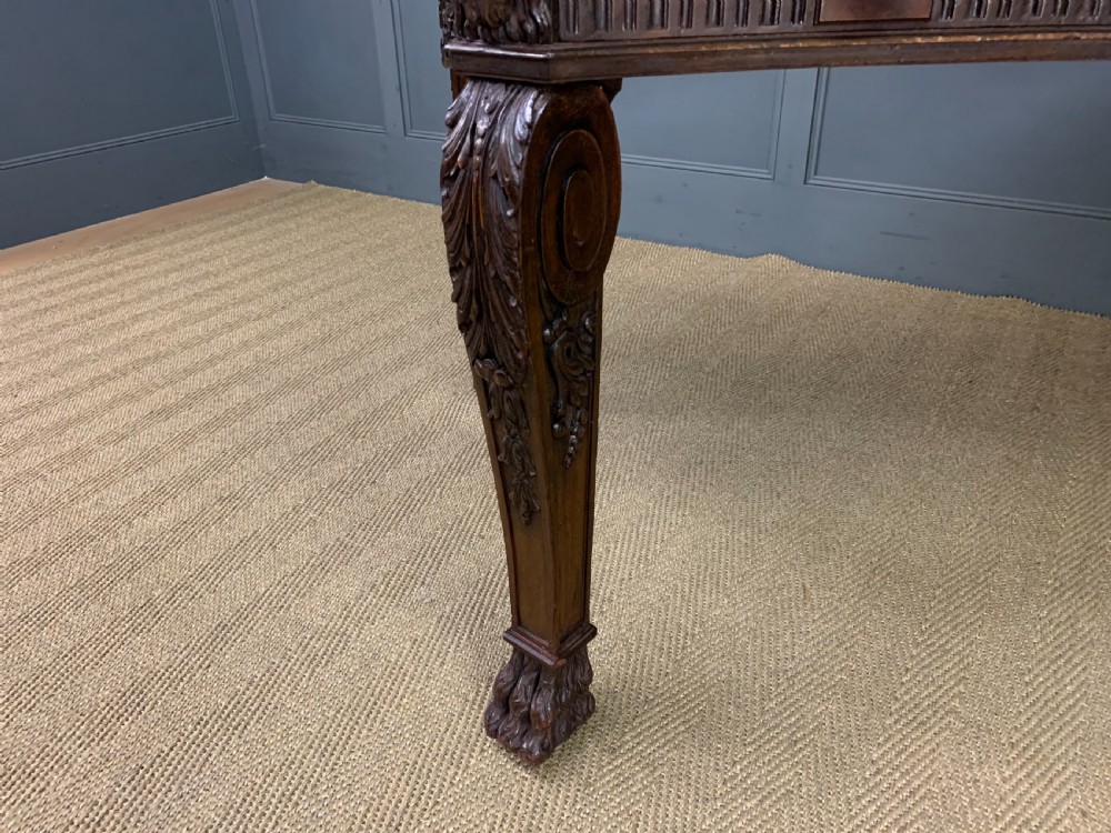A carved mahogany writing table with a three-section inset leather top, detailed frieze carvings, and carved legs with claw feet. View XV