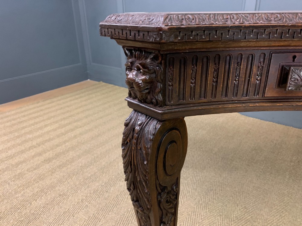 A carved mahogany writing table with a three-section inset leather top, detailed frieze carvings, and carved legs with claw feet. View XVI