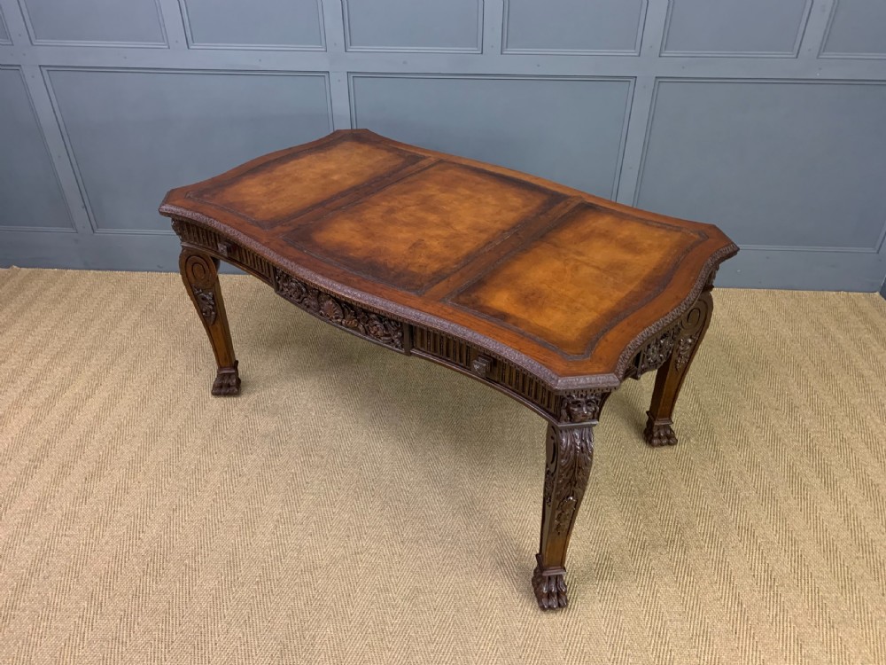 A carved mahogany writing table with a three-section inset leather top, detailed frieze carvings, and carved legs with claw feet. View XVIII