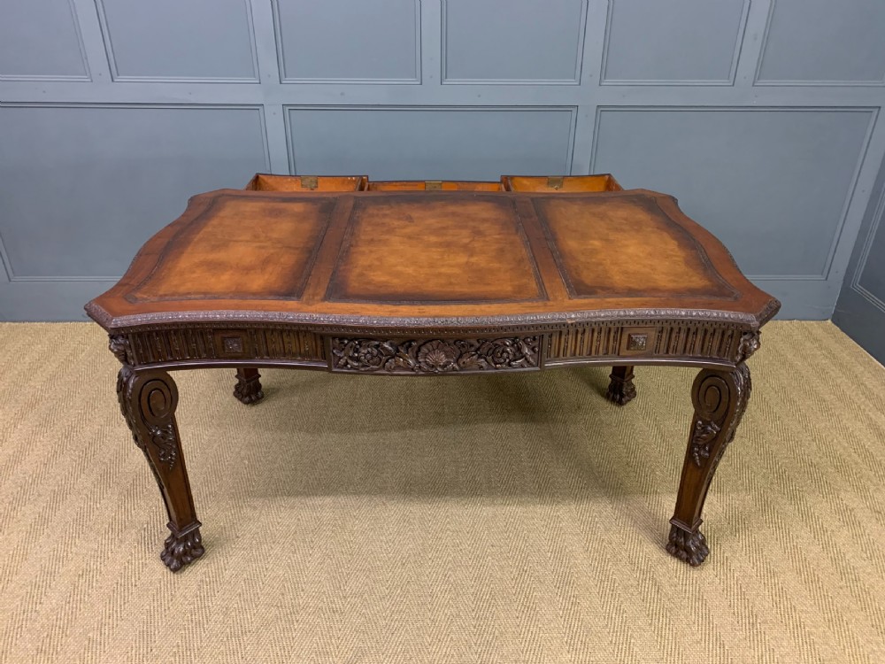 A carved mahogany writing table with a three-section inset leather top, detailed frieze carvings, and carved legs with claw feet. View XX