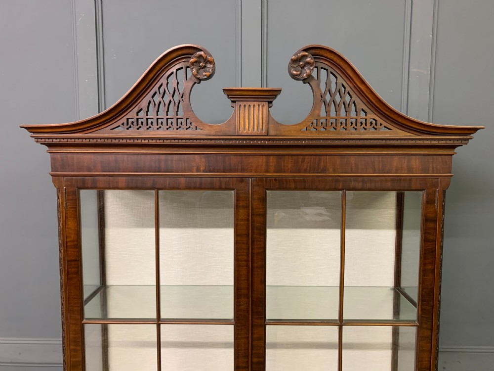 A Chippendale style mahogany display cabinet featuring a swan-neck pediment, glazed twin doors, internal glass shelves, and carved feet. View III