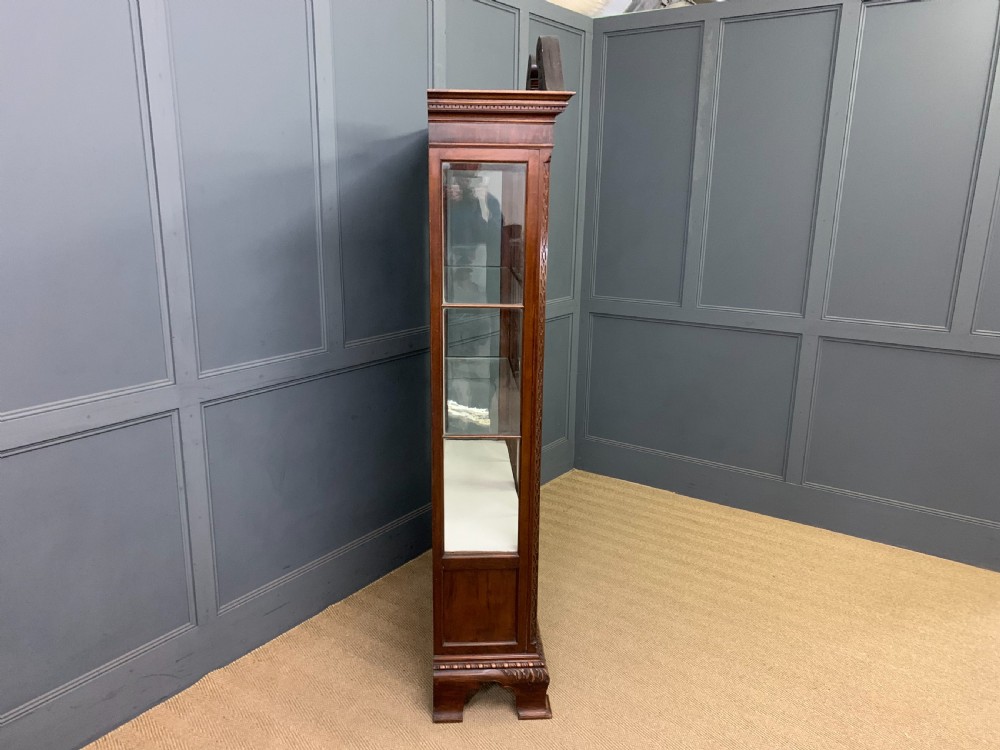 A Chippendale style mahogany display cabinet featuring a swan-neck pediment, glazed twin doors, internal glass shelves, and carved feet. View VIII