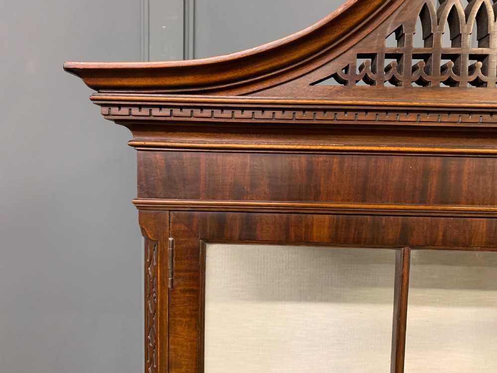 A Chippendale style mahogany display cabinet featuring a swan-neck pediment, glazed twin doors, internal glass shelves, and carved feet. View XVI