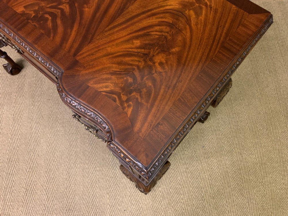 A flame mahogany Chippendale style writing desk featuring a shaped top, five brass-handled drawers, and carved cabriole legs with ball and claw feet. View IX