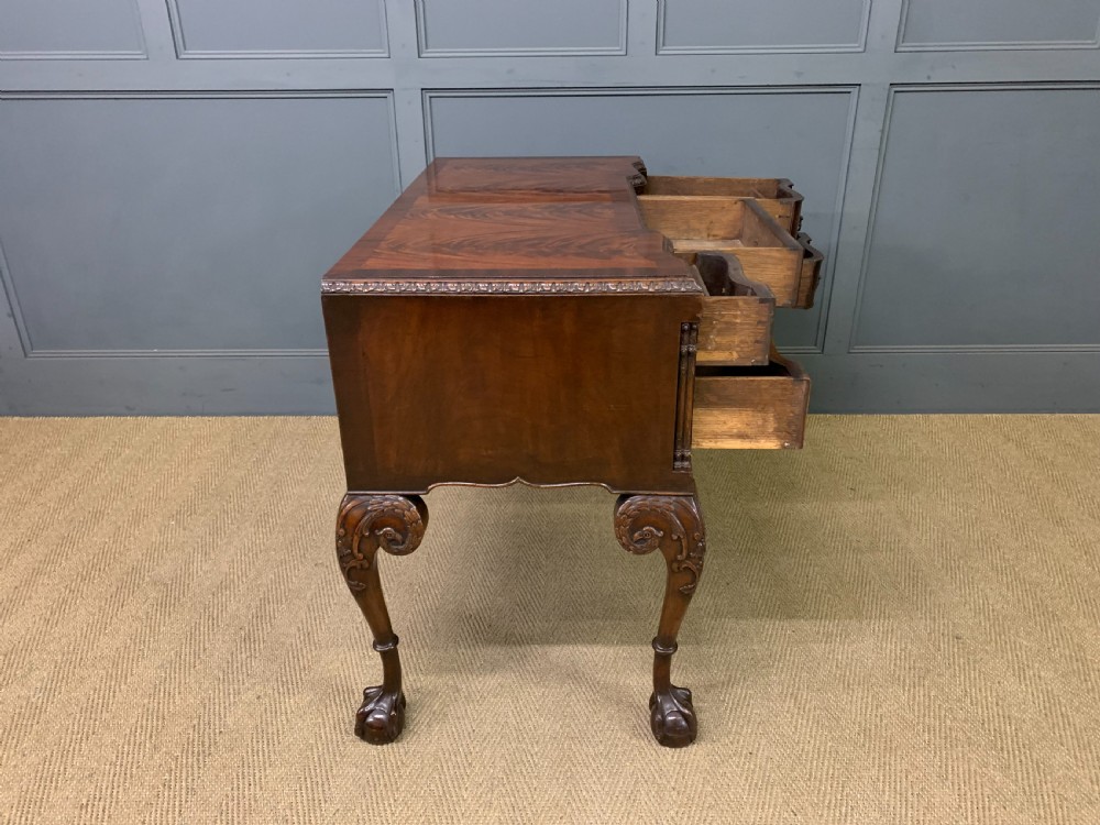 A flame mahogany Chippendale style writing desk featuring a shaped top, five brass-handled drawers, and carved cabriole legs with ball and claw feet. View XIII