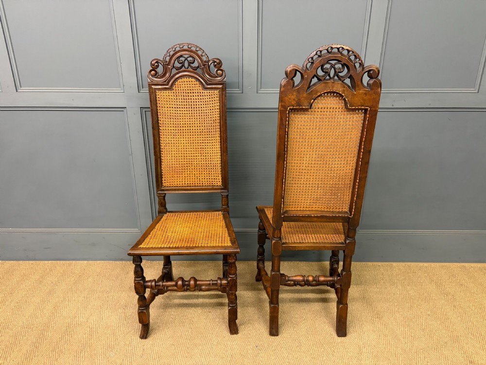A set of three dark timber Carolean style side chairs featuring high arched carved cresting, woven cane backrest panels, cane seats, and turned stretchers. View XII