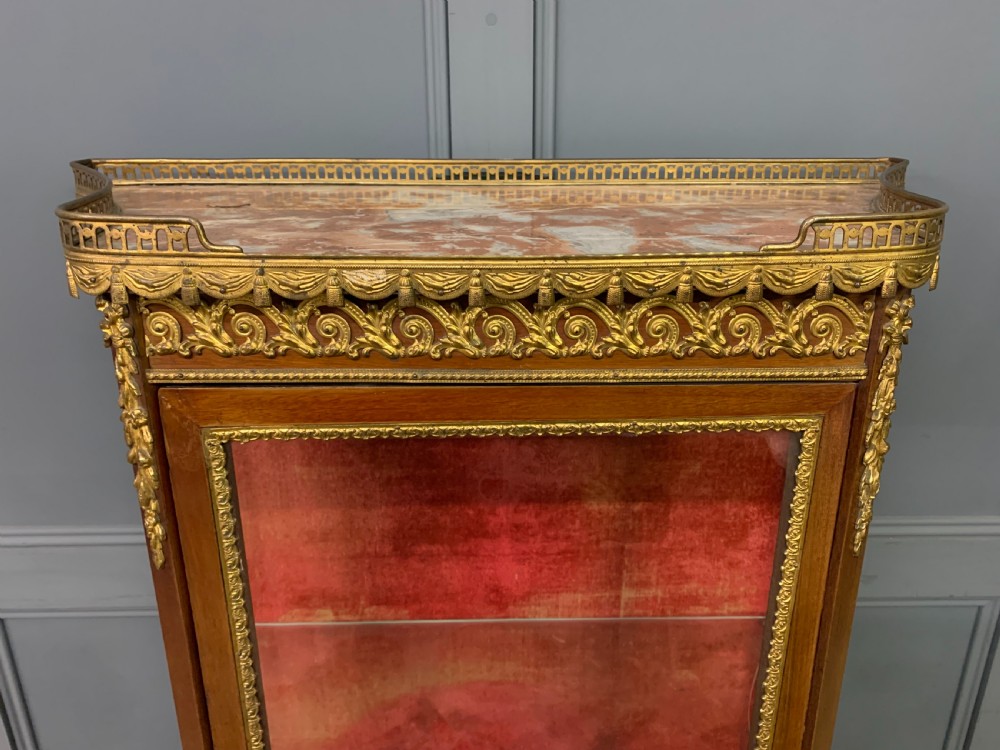 A French Louis XV style mahogany vitrine featuring a curved glazed door, gilt-bronze mounts, hand-painted lower panel depicting romantic figures, and a red velvet interior. View IV