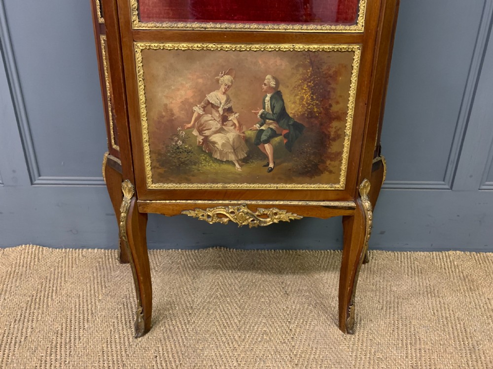 A French Louis XV style mahogany vitrine featuring a curved glazed door, gilt-bronze mounts, hand-painted lower panel depicting romantic figures, and a red velvet interior. View VI