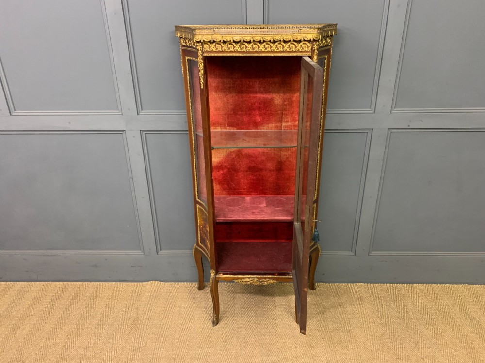 A French Louis XV style mahogany vitrine featuring a curved glazed door, gilt-bronze mounts, hand-painted lower panel depicting romantic figures, and a red velvet interior. View IX
