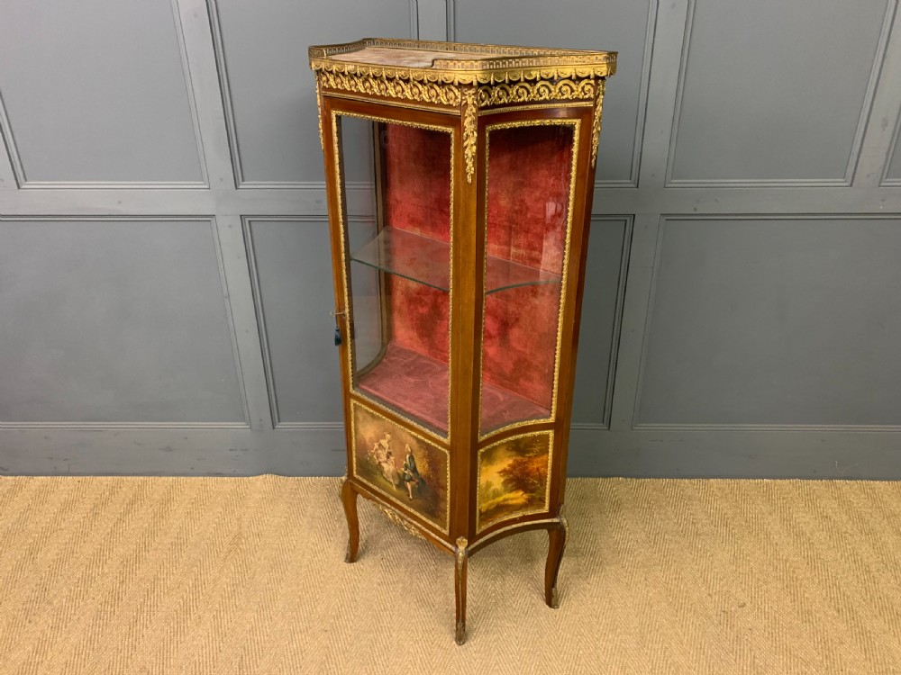A French Louis XV style mahogany vitrine featuring a curved glazed door, gilt-bronze mounts, hand-painted lower panel depicting romantic figures, and a red velvet interior. View XIV