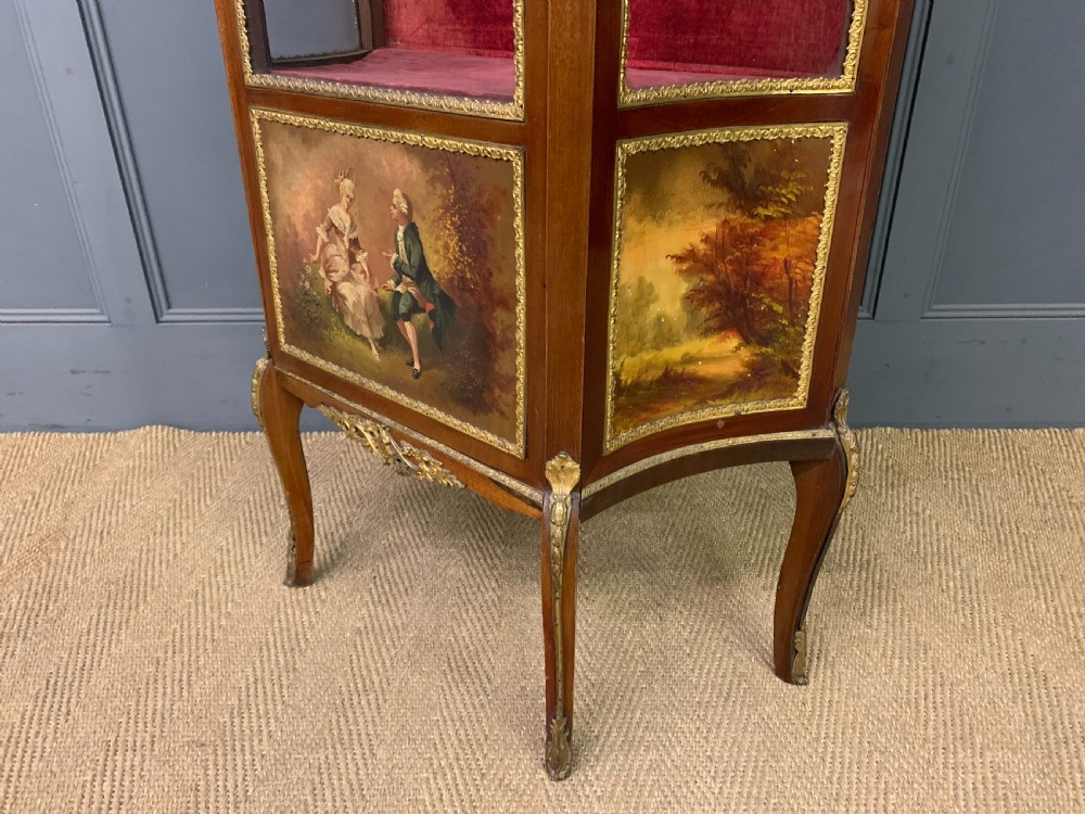 A French Louis XV style mahogany vitrine featuring a curved glazed door, gilt-bronze mounts, hand-painted lower panel depicting romantic figures, and a red velvet interior. View XV