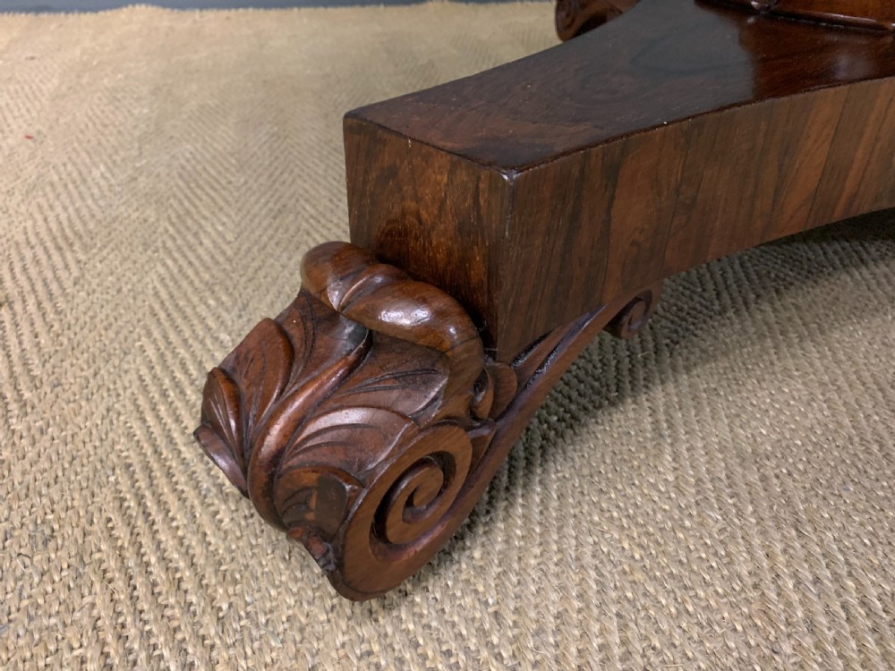 A William IV rosewood tilt-top loo table featuring a richly figured oval top mounted on a turned pedestal and a tri-form base with carved feet. View VIII