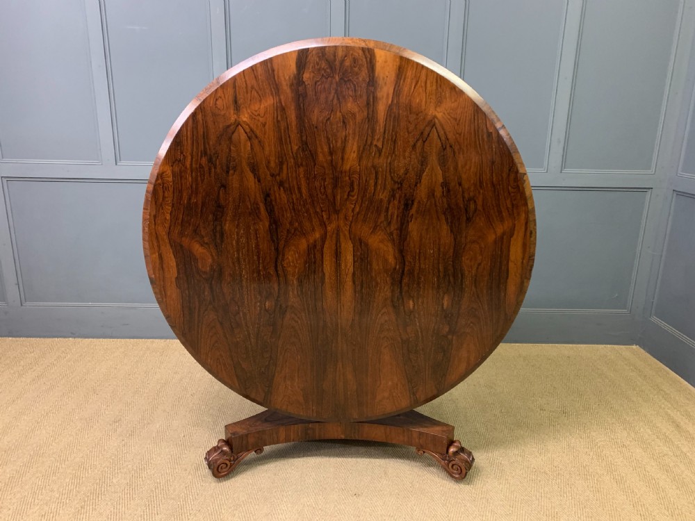 A William IV rosewood tilt-top loo table featuring a richly figured oval top mounted on a turned pedestal and a tri-form base with carved feet. View XII