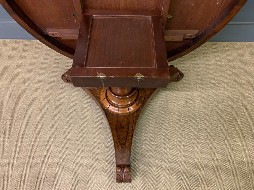 A William IV rosewood tilt-top loo table featuring a richly figured oval top mounted on a turned pedestal and a tri-form base with carved feet. View XVI