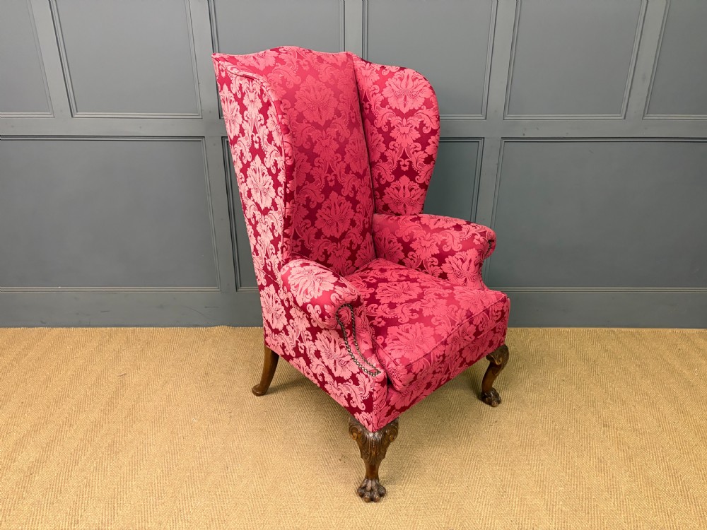 Late nineteenth-century wingback armchair upholstered in red damask fabric, featuring carved walnut cabriole legs with claw and ball feet. View VI