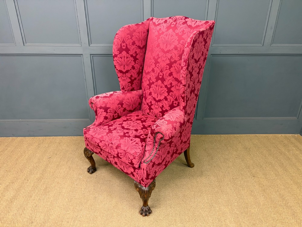 Late nineteenth-century wingback armchair upholstered in red damask fabric, featuring carved walnut cabriole legs with claw and ball feet. View X