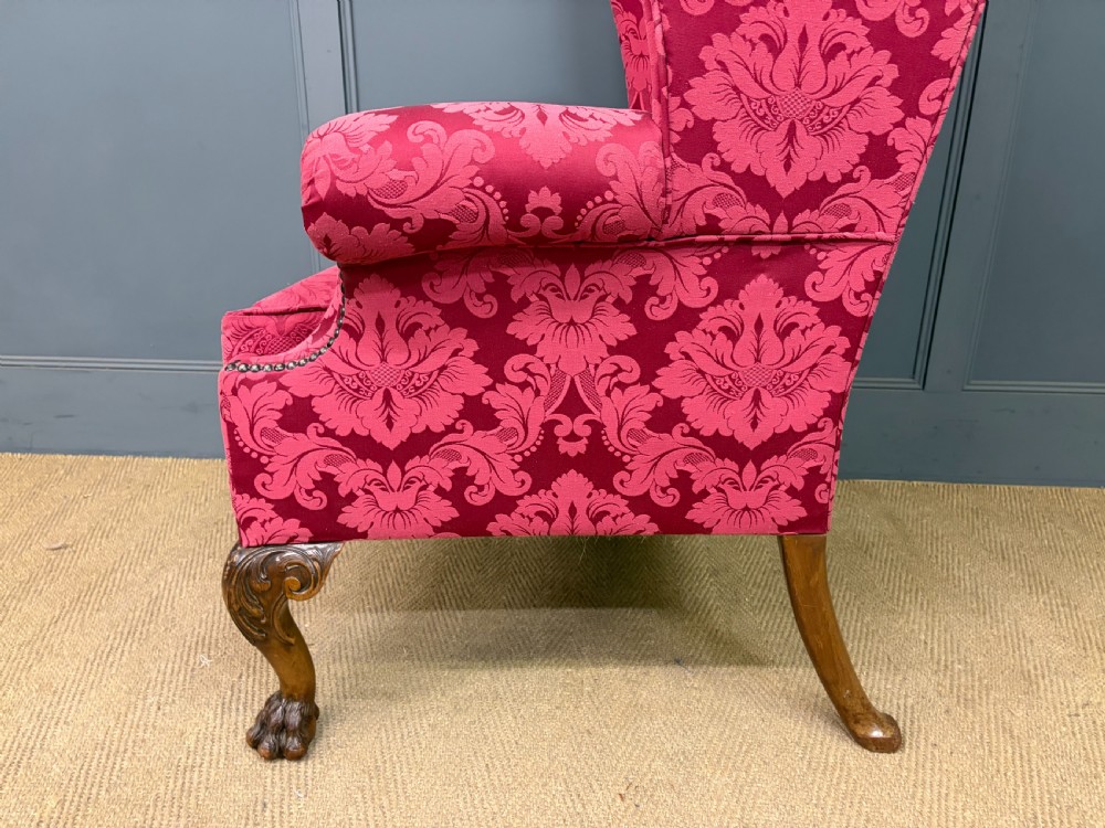 Late nineteenth-century wingback armchair upholstered in red damask fabric, featuring carved walnut cabriole legs with claw and ball feet. View XII
