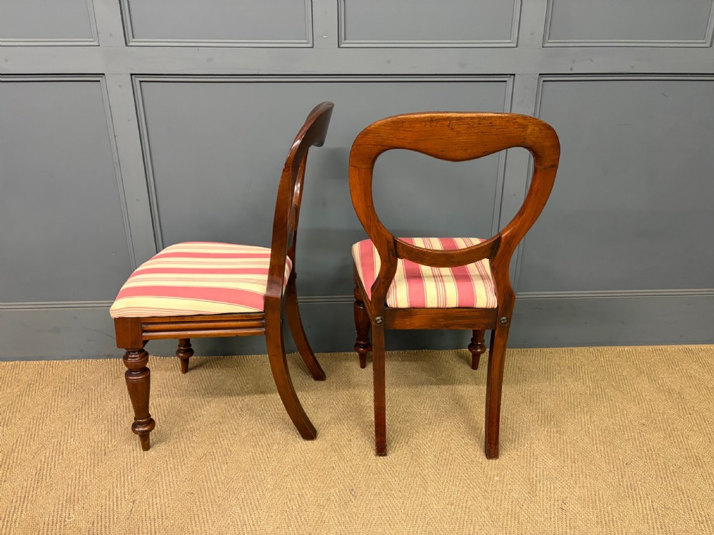 A set of ten Victorian mahogany balloon back dining chairs featuring turned front legs and red and cream striped upholstered seats. View V