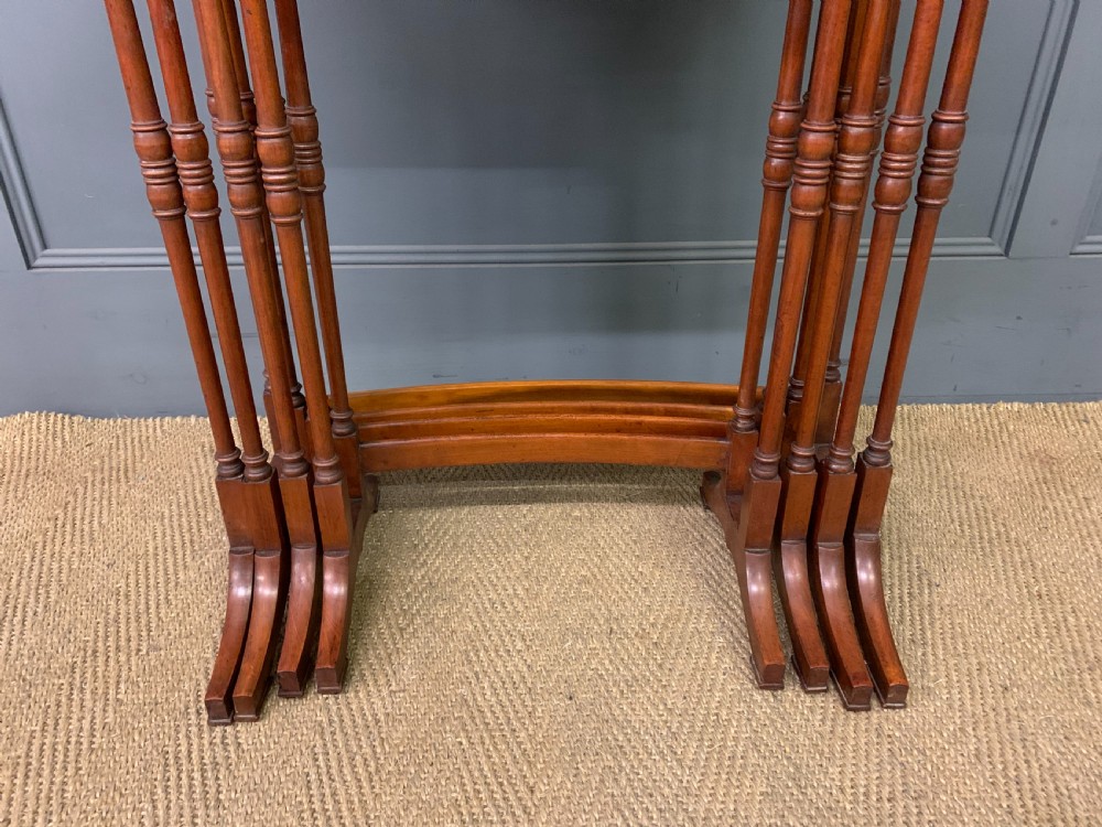 A nest of four graduated wooden tables featuring figure-grained satinwood tops with inlaid borders and slender turned legs. View IV