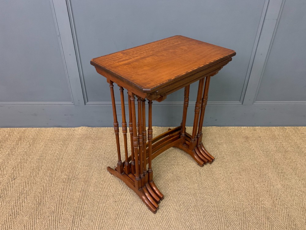 A nest of four graduated wooden tables featuring figure-grained satinwood tops with inlaid borders and slender turned legs. View V